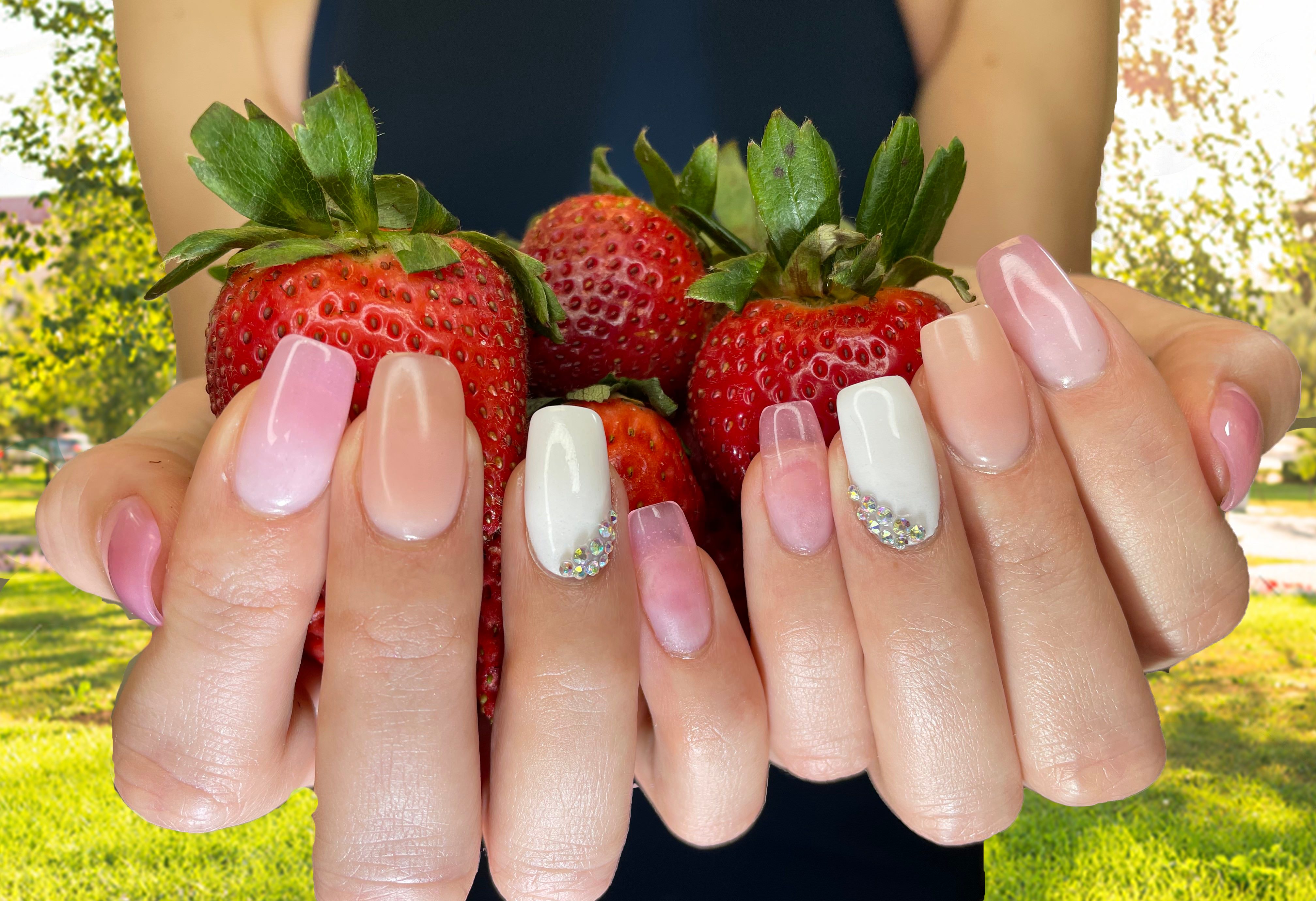 pink and white acrylic nails holding strawberries